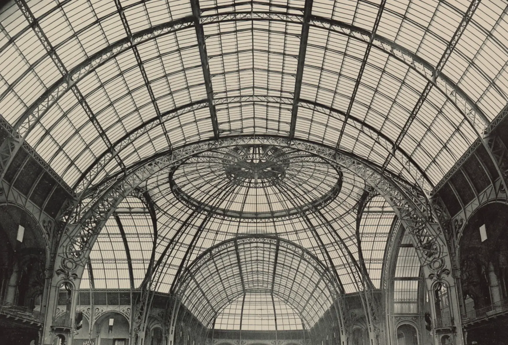 Ornate iron-and-glass vaulted ceiling with a circular central skylight and arched hallways below