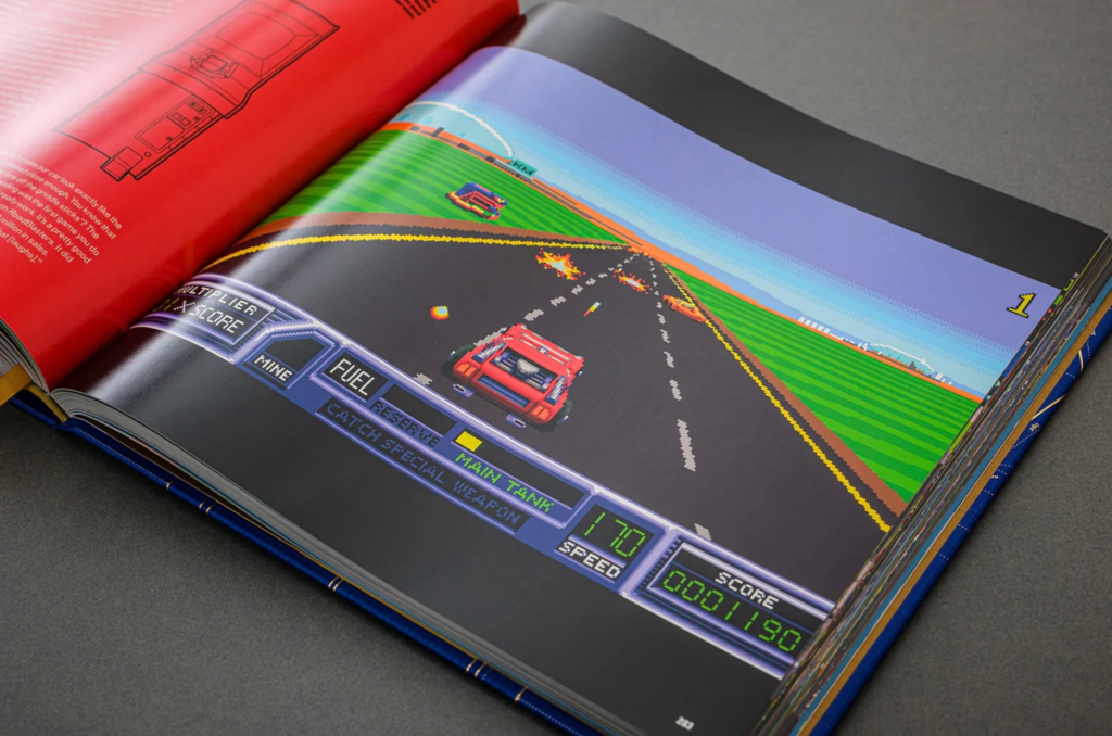 Open book showing a pixel-art red race car on a road, with a racing-game dashboard and bright green fields