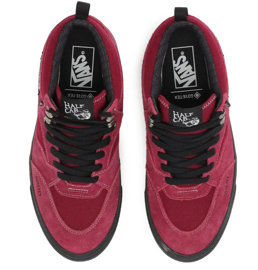 Top-down view of matching red and black Half Cab skate shoes with black laces and white logos on a white background