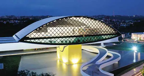 Oscar Niemeyer Museum’s eye-shaped building with a glowing yellow cube in the foreground at dusk