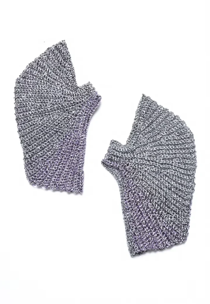 Two separate metallic silver knitted fabric pieces with angular, pleated shapes on a white background