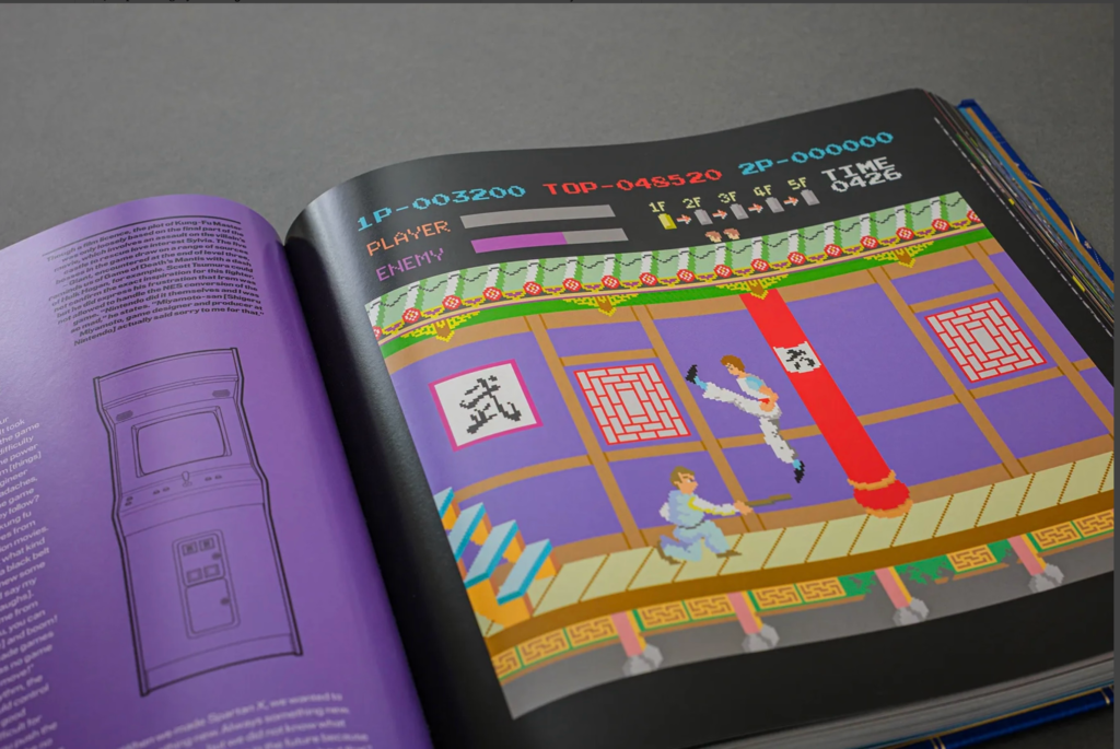 Open book showing a colorful pixel-art fighting game screen, with two martial artists, a red pillar, and game statistics