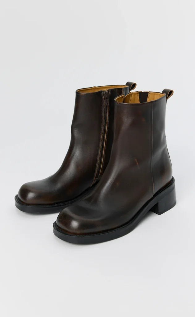 Pair of dark brown leather ankle boots with side zippers, pull tabs, rounded toes and black block heels on a white background