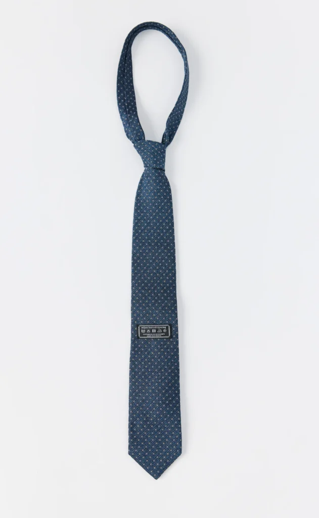 Blue patterned necktie laid flat on a white background, with a small black label near the lower end