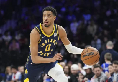 Tyrese Haliburton dribbles a basketball in a navy and yellow Indiana Pacers uniform before a blurred crowd
