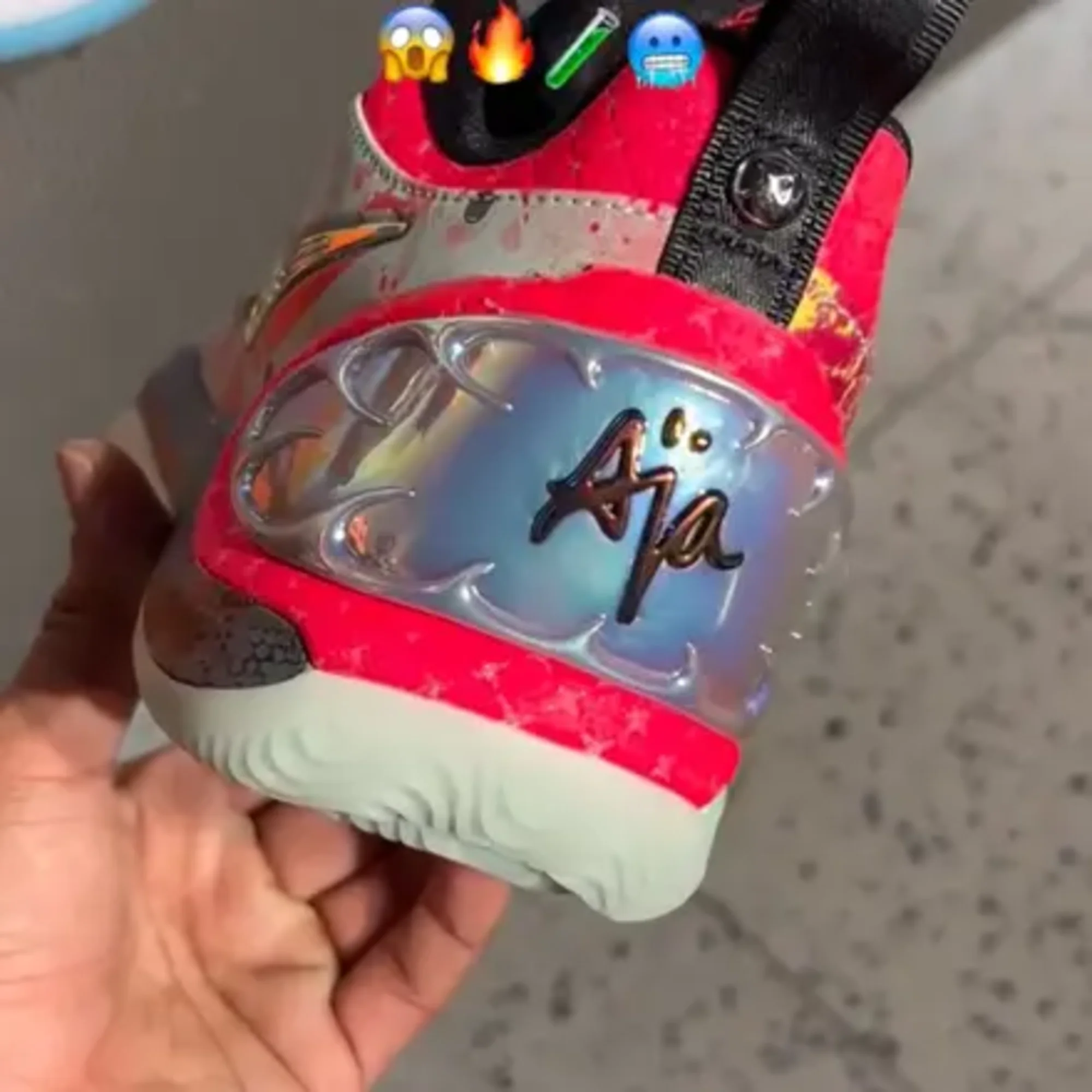 Close-up of a red and gray Nike basketball shoe held in a hand, featuring a translucent panel with A'ja Wilson's signature