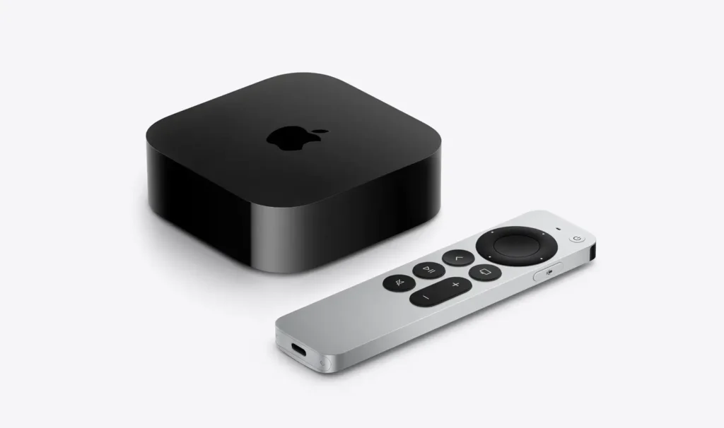 Black Apple TV box and silver remote with black buttons arranged on a white background