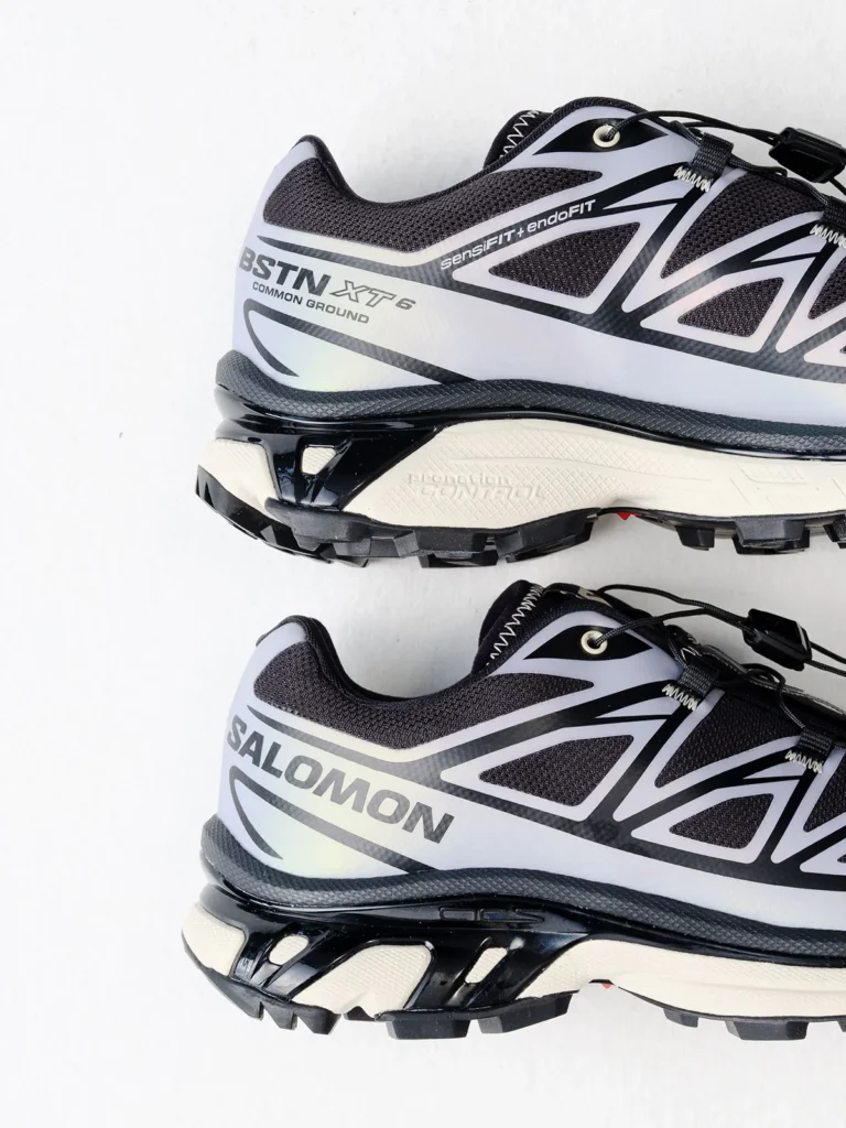 Two black, white and gray Salomon XT-6 trail shoes stacked on a white background, showing lugged soles and quick-lace systems