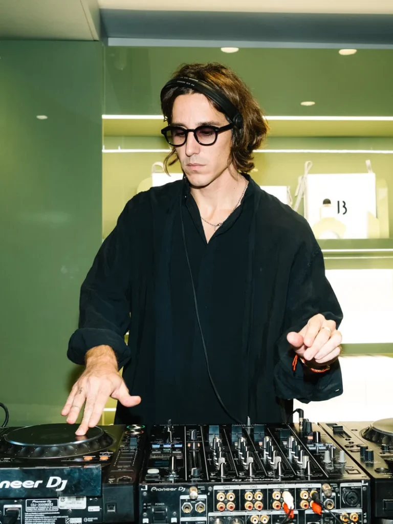 DJ in black operating a Pioneer mixer and turntables in a brightly lit store_久久爱