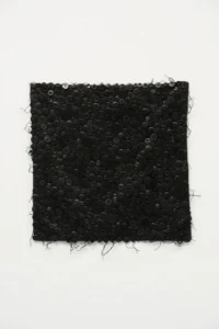 Rectangular black textile panel densely covered with buttons and loose threads, isolated against a white background
