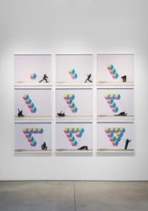Nine frame panels show a black-clad figure pulling colorful geometric cubes into changing formations on a white wall