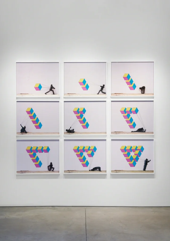 Nine frame panels show a black-clad figure pulling colorful geometric cubes into changing formations on a white wall