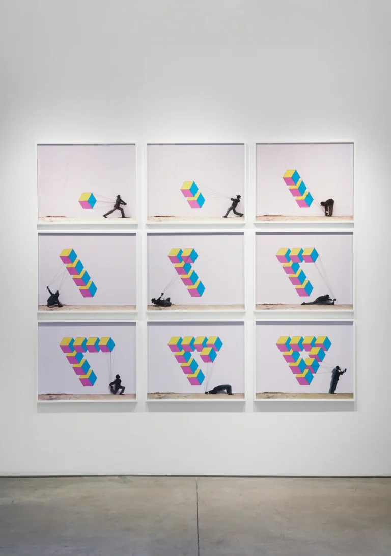 Nine frame panels show a black-clad figure pulling colorful geometric cubes into changing formations on a white wall
