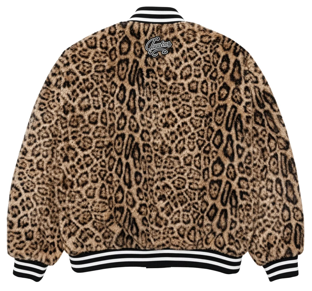 Back of a tan leopard-print varsity jacket with black-and-white striped ribbing and a Wacko Maria logo near the collar