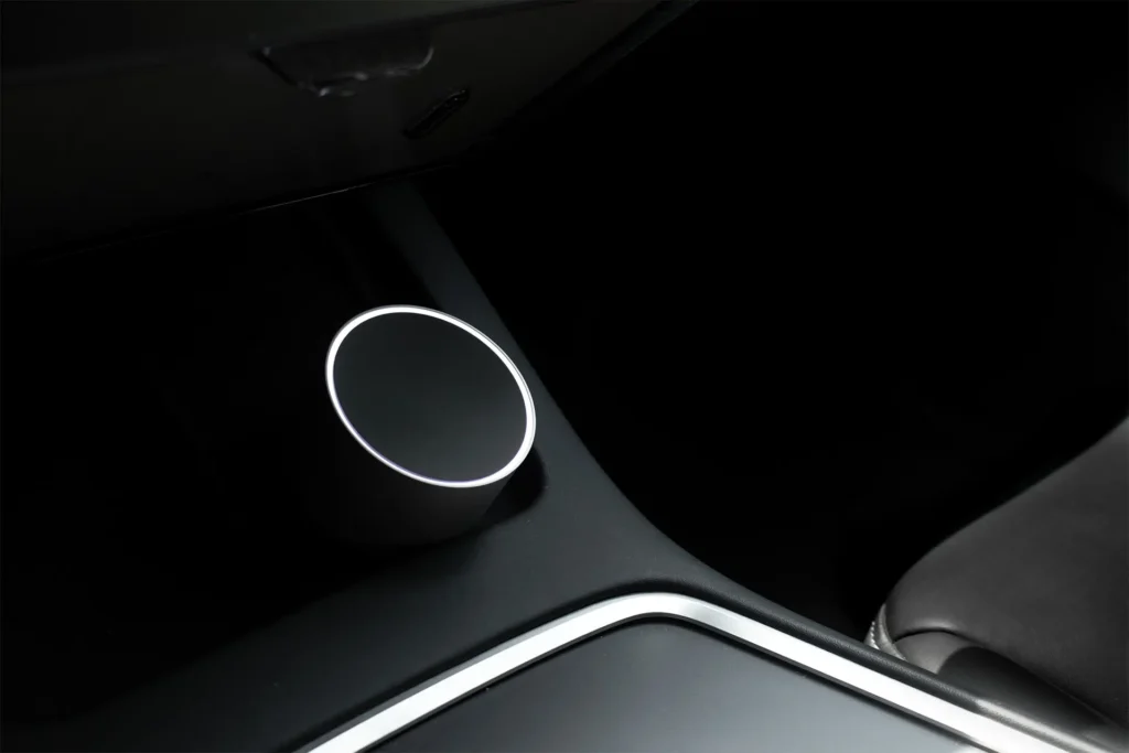 Close-up of a circular car diffuser mounted beside the center console, with illuminated rim and dark interior surrounding it