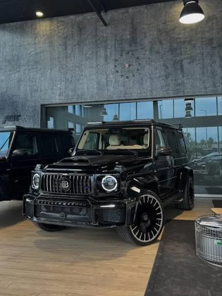 Black BRABUS G-Class SUV displayed indoors beside another vehicle
