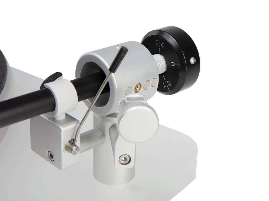 Close-up of a white tonearm assembly with a black counterweight and numbered adjustment dial against a white background