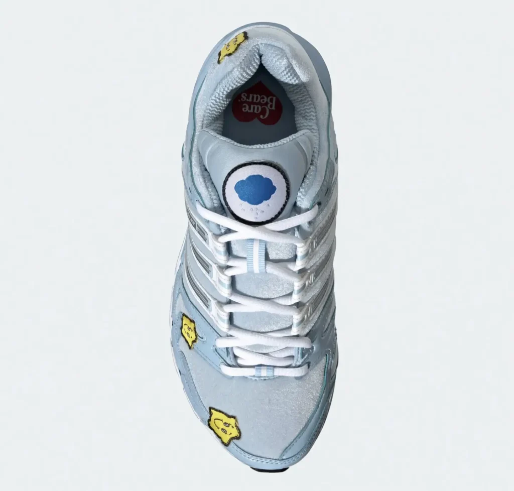 Top-down view of a light blue and white sneaker with white laces and yellow cartoon patches on a pale background