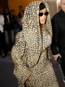 Cardi B wears a leopard-print hooded outfit and black oval sunglasses while walking past onlookers indoors