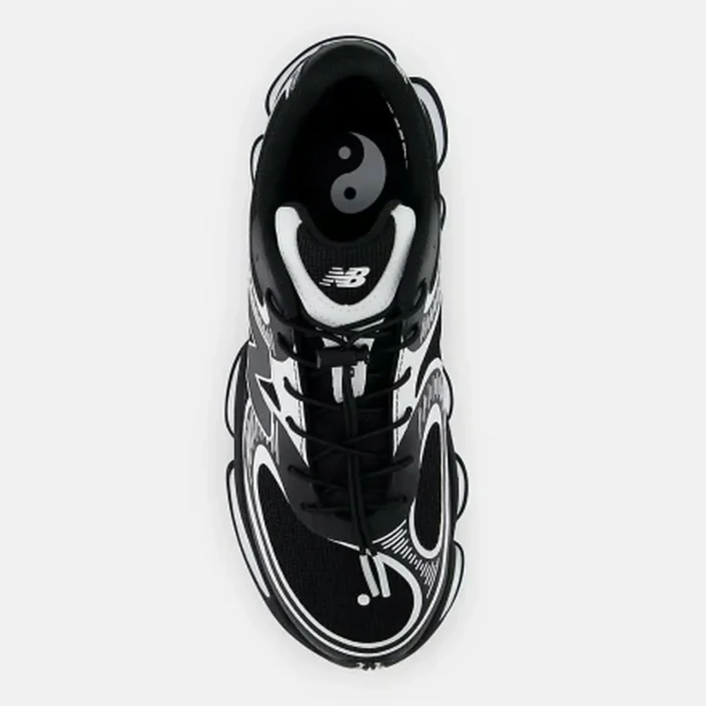 Top-down view of a black-and-white New Balance shoe with yin-yang insole graphic and laces on a white background