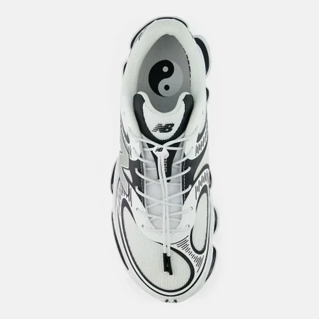 Top-down view of a white and black New Balance sneaker with yin-yang graphic on the insole and white laces