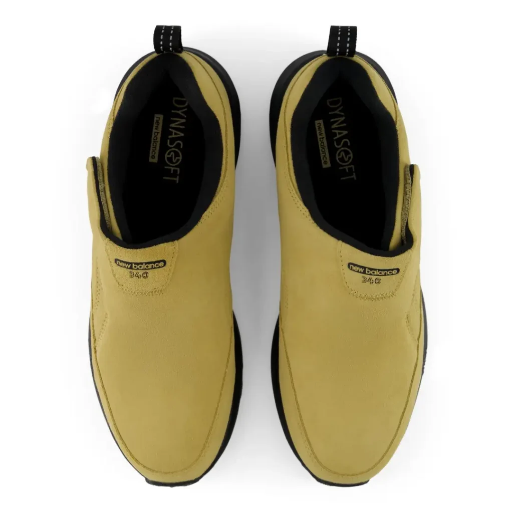 Top view of paired mustard-yellow New Balance slip-on shoes with black lining and pull tabs on a white background