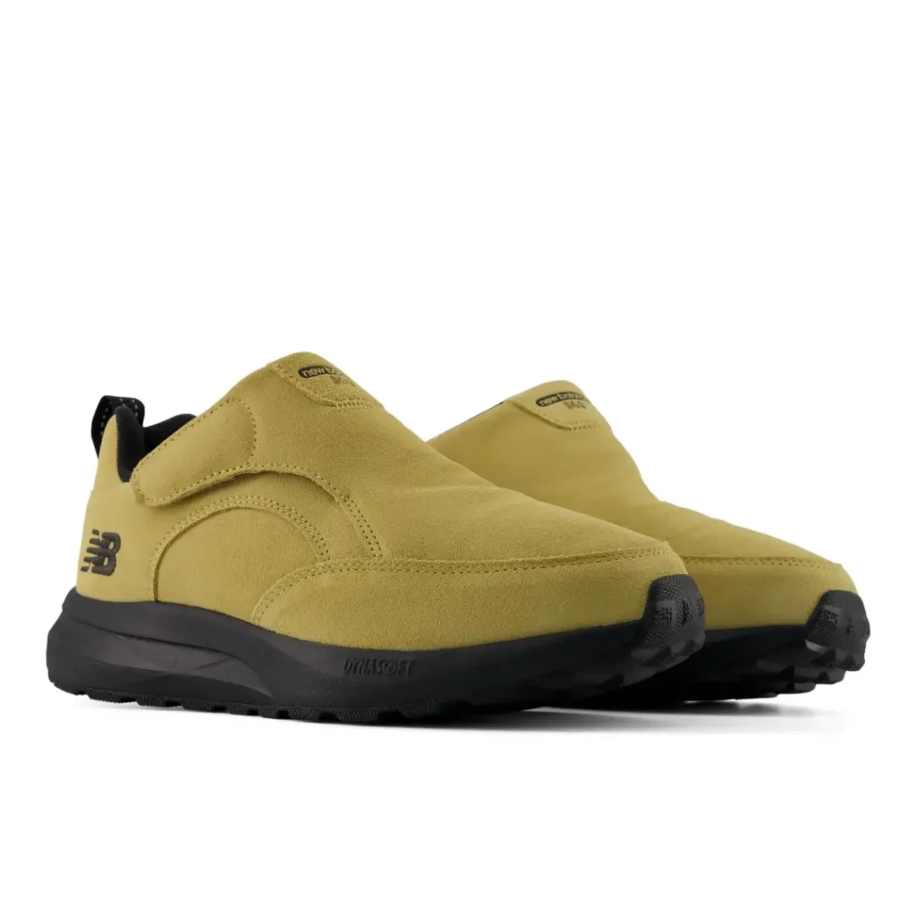 Pair of mustard-yellow suede New Balance slip-on shoes with black soles and toe caps on a white background