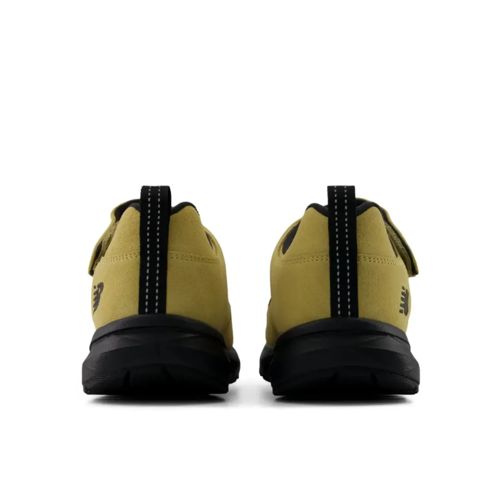 Rear view of matching mustard suede sneakers with black soles and vertical black pull tabs on a white background