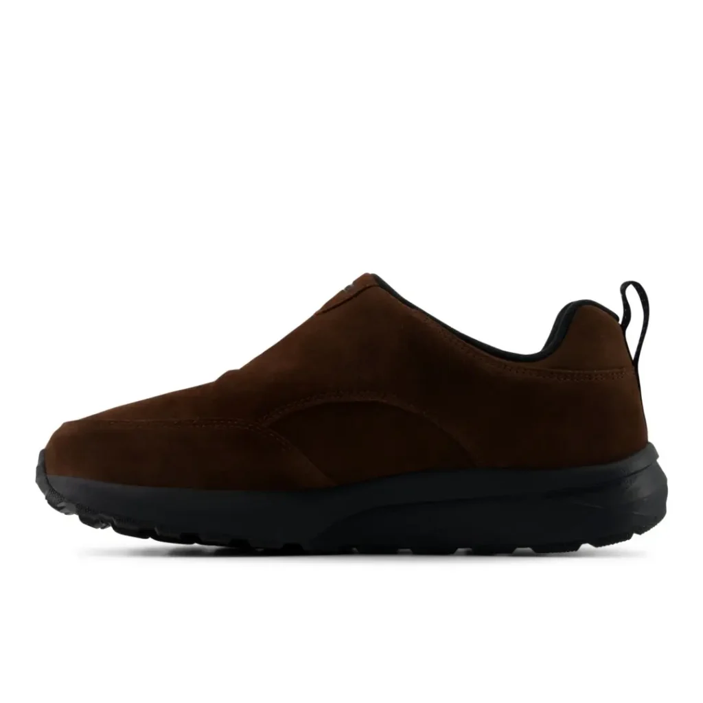 Brown low-top sneaker with a suede upper, black sole, and heel pull tab shown in side profile on white background