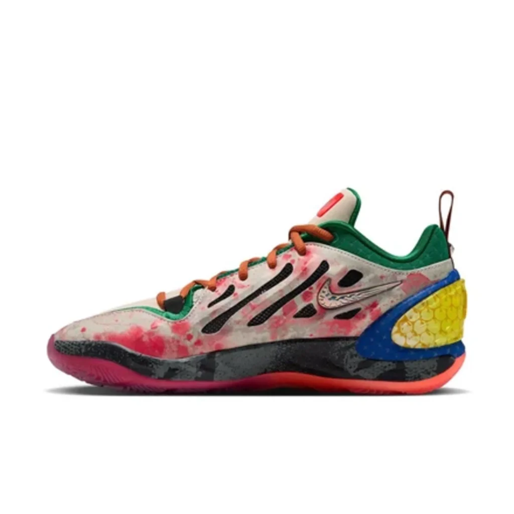 Low-top Nike basketball shoe with pink splatter, green lining, orange laces, black overlays, blue midsole and yellow heel