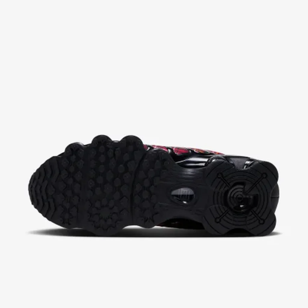 Black Nike Shox sneaker shown from the sole, featuring rounded cushioning pods and a circular tread pattern on a white