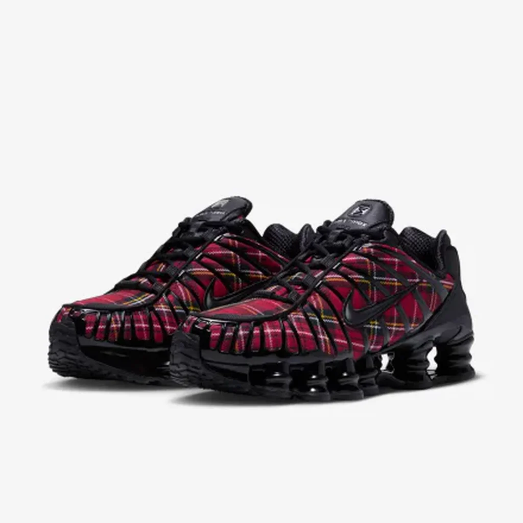 Pair of black Nike sneakers with red and multicolor plaid uppers and segmented Shox cushion on a white background