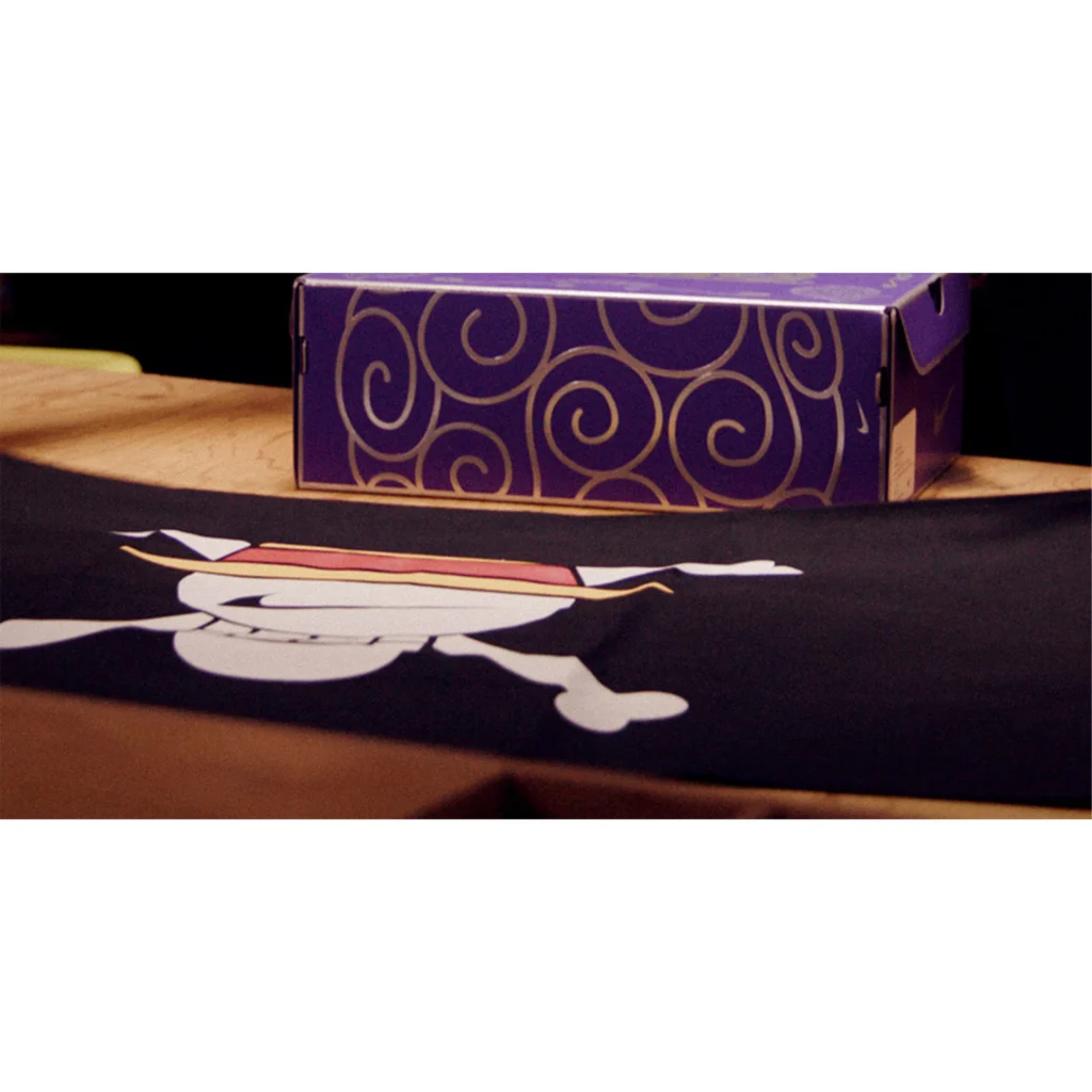 Purple patterned box on a wooden table beside a black pirate flag with a skull and crossed bones
