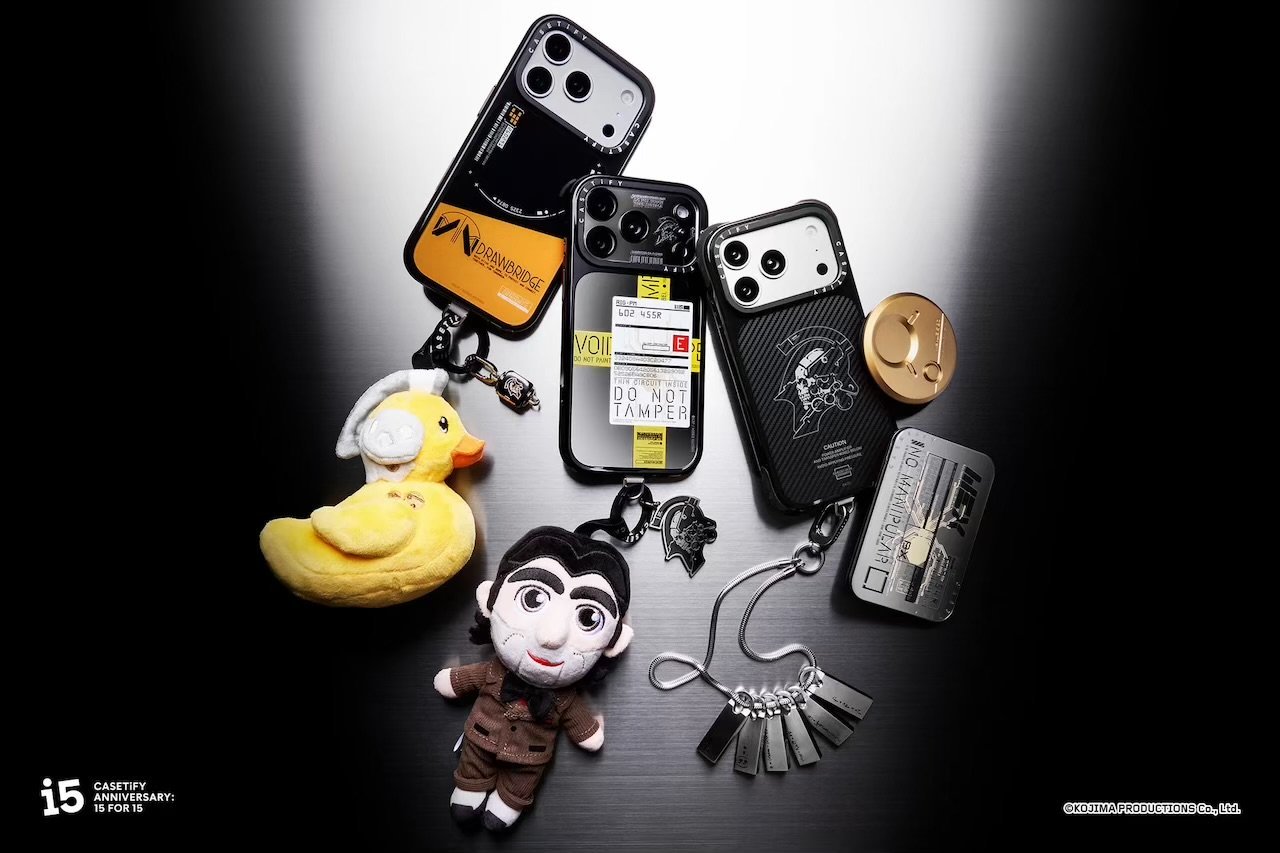 Three character-themed phone cases and metal accessories arranged with yellow duck and suited plush toys on a dark surface