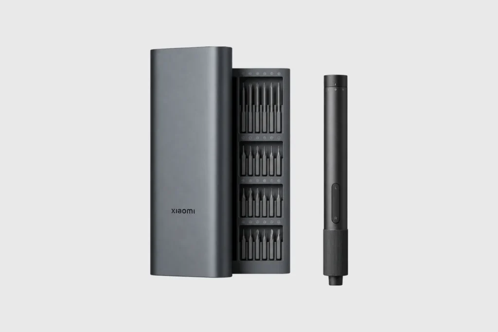 Xiaomi cordless precision screwdriver, bit case, and gray metal storage sleeve arranged against a light gray background