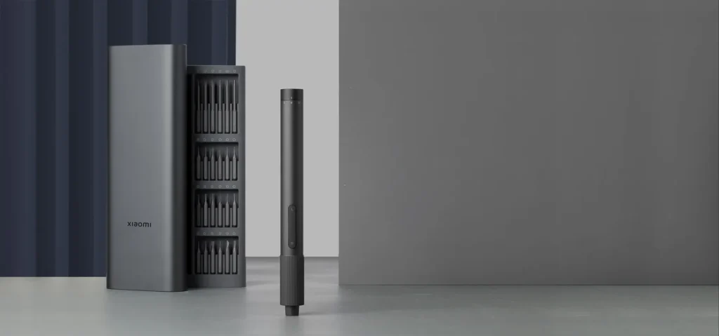 Xiaomi precision screwdriver, bit case, and silver metal storage box arranged on a gray surface